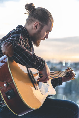 A man with a beard plays the acoustic guitar.の写真素材