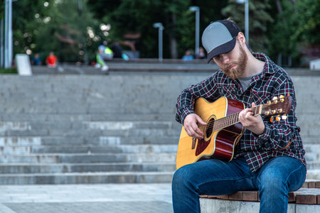 Male street musician plays the acoustic guitar.
