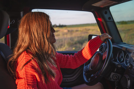 A young woman driving an SUV in the countryside.の写真素材