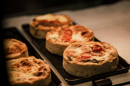 Small puff pies with vegetables and meat, quiches in a cafe window.の写真素材