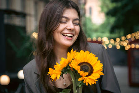 Portrait of a young woman with a bouquet of sunflowers.の写真素材