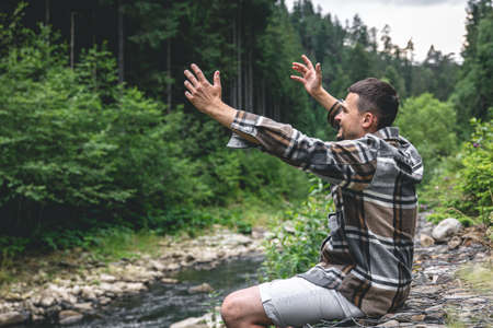 A young man in the forest near the river enjoys nature, a halt.の写真素材