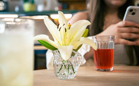 Close-up, lily flower in a vase on a table in a cafe.の写真素材
