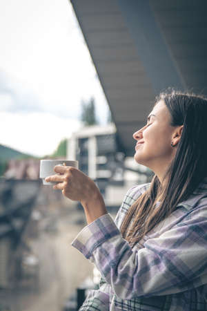 A woman drinking coffee on the balcony in the morning.の写真素材