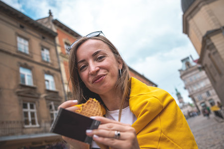 A young woman tourist eats ice cream on a city walk.