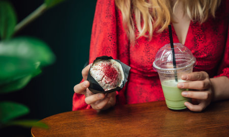 Ice matcha latte and cupcake close-up in a cafe in female hands.