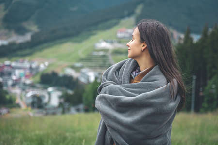 A young woman wrapped in a blanket in the mountains.の写真素材