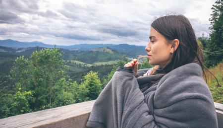 A young woman drinking coffee overlooking the mountains.