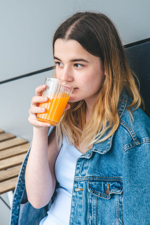 Woman drinks orange juice in a cafe, close-up.