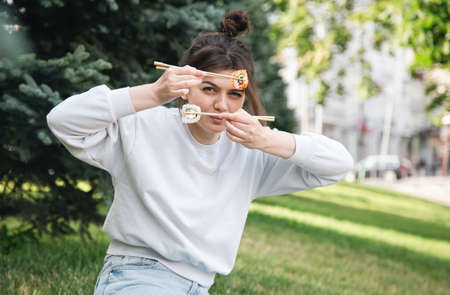 A young woman eating sushi in the park, picnic in nature.の写真素材