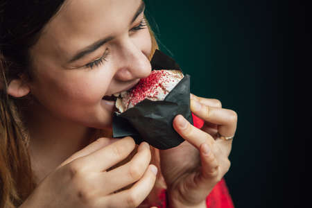 A young woman enjoys a raspberry muffin in a cafe.の写真素材