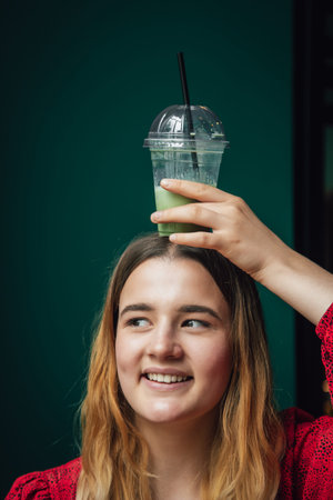 A young woman in a cafe drinks a green drink ice latte.