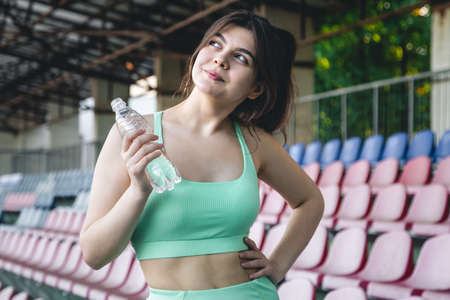 A young woman with a bottle of water in training at the stadium.の写真素材