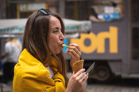 A young woman tourist eats ice cream on a city walk.の写真素材