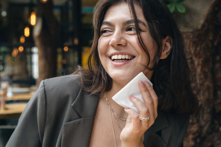 Happy young woman with a napkin near her mouth in a restaurant.の写真素材