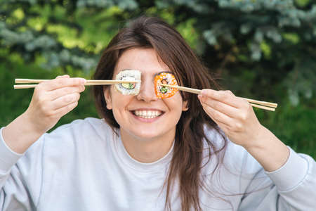 A young woman eating sushi in the park, picnic in nature.の写真素材
