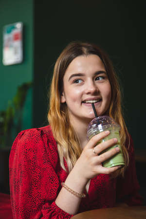 A young woman in a cafe drinks a green drink ice latte.の写真素材