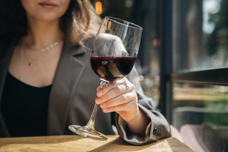 Close-up, a glass of wine in female hands in a cafe.