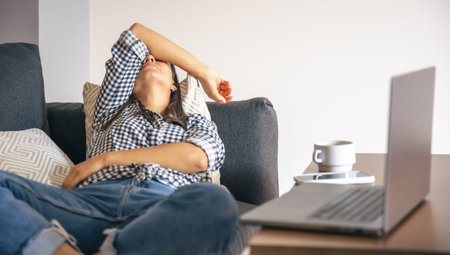 Tired from work young woman in front of a laptop.