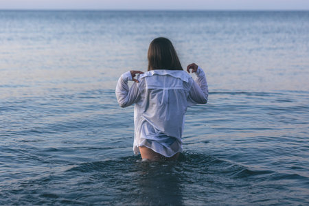 A woman in a bathing suit and a white shirt in the sea.の写真素材