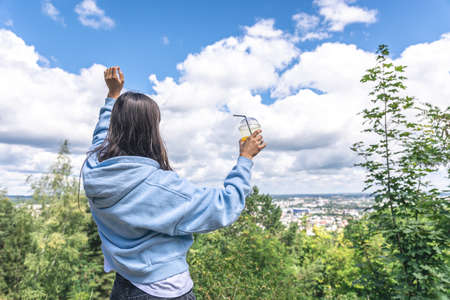 A young woman drinking juice from a straw in the park.の写真素材