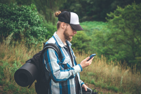 A male traveler with a backpack looks into a smartphone.