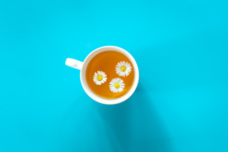 A cup of chamomile tea on blue background, flat lay.の写真素材
