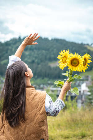 Woman with a bouquet of sunflowers in nature in a mountainous area.の写真素材