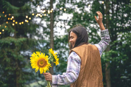 A young woman with a bouquet of sunflowers on a blurred background in nature.の写真素材
