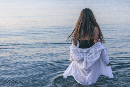 A woman in a bathing suit and a white shirt in the sea.の写真素材