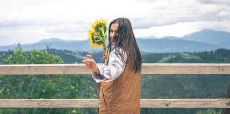Woman with a bouquet of sunflowers in nature in the mountains.の写真素材