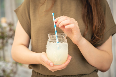 Close-up, a glass of lemonade in female hands.の写真素材