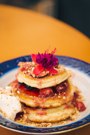 Appetizing pancakes decorated with berries and flowers.