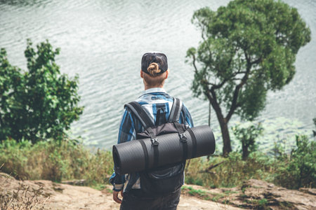 Male traveler with backpack and karimat in nature, back view.の写真素材
