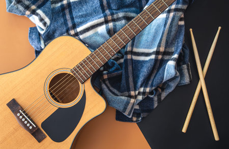 Music background with guitar and drumsticks, top view.