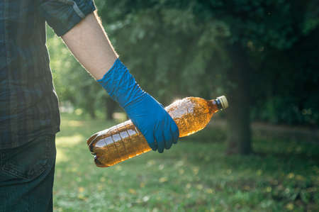 Close-up, a plastic bottle in a male hand, cleaning up nature.の写真素材