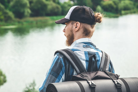 Male traveler with backpack and karimat in nature, back view.