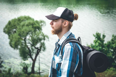 Male traveler with backpack and karimat in nature by the lake.の写真素材