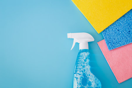 Blank cleaning spray bottle and colored rags on blue background, flat lay.の写真素材