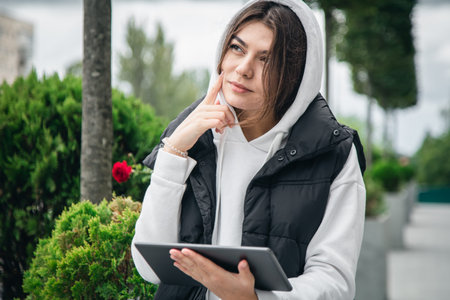 Attractive young woman holding a tablet outside.