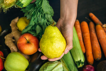 Close-up, an pear in a female hand on a blurred background with vegetables.