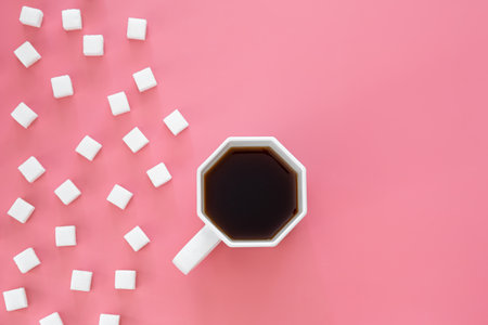 Cup of coffee and sugar in cubes on a pink background, flat lay.の写真素材