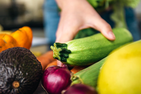 Close-up, zucchini in female hands among vegetables on the kitchen table.の写真素材