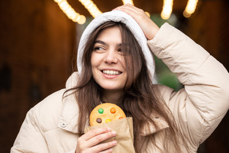 Attractive young woman with gingerbread on a blurred background with bokeh.