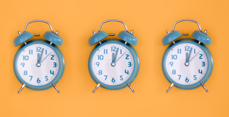 Blue alarm clocks on orange background isolated, flat lay.の写真素材