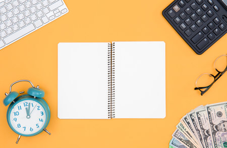 Flat lay, notebook, money, calculator and alarm clock on orange background.の写真素材