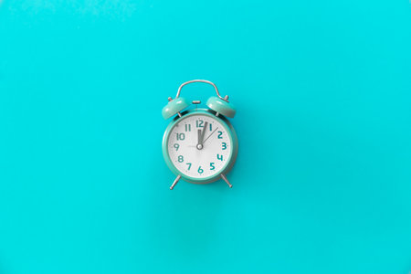 Blue alarm clock on blue background isolated, flat lay.の写真素材