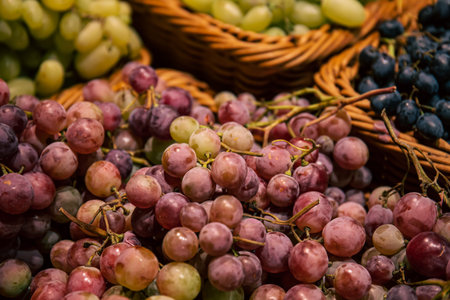 Baskets with different types of grapes on a supermarket showcase.