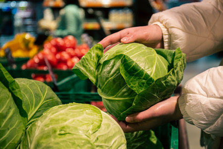A woman chooses cabbage in a grocery store, close-up.の写真素材