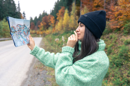 A young woman with a road map in the forest in the mountains.の写真素材